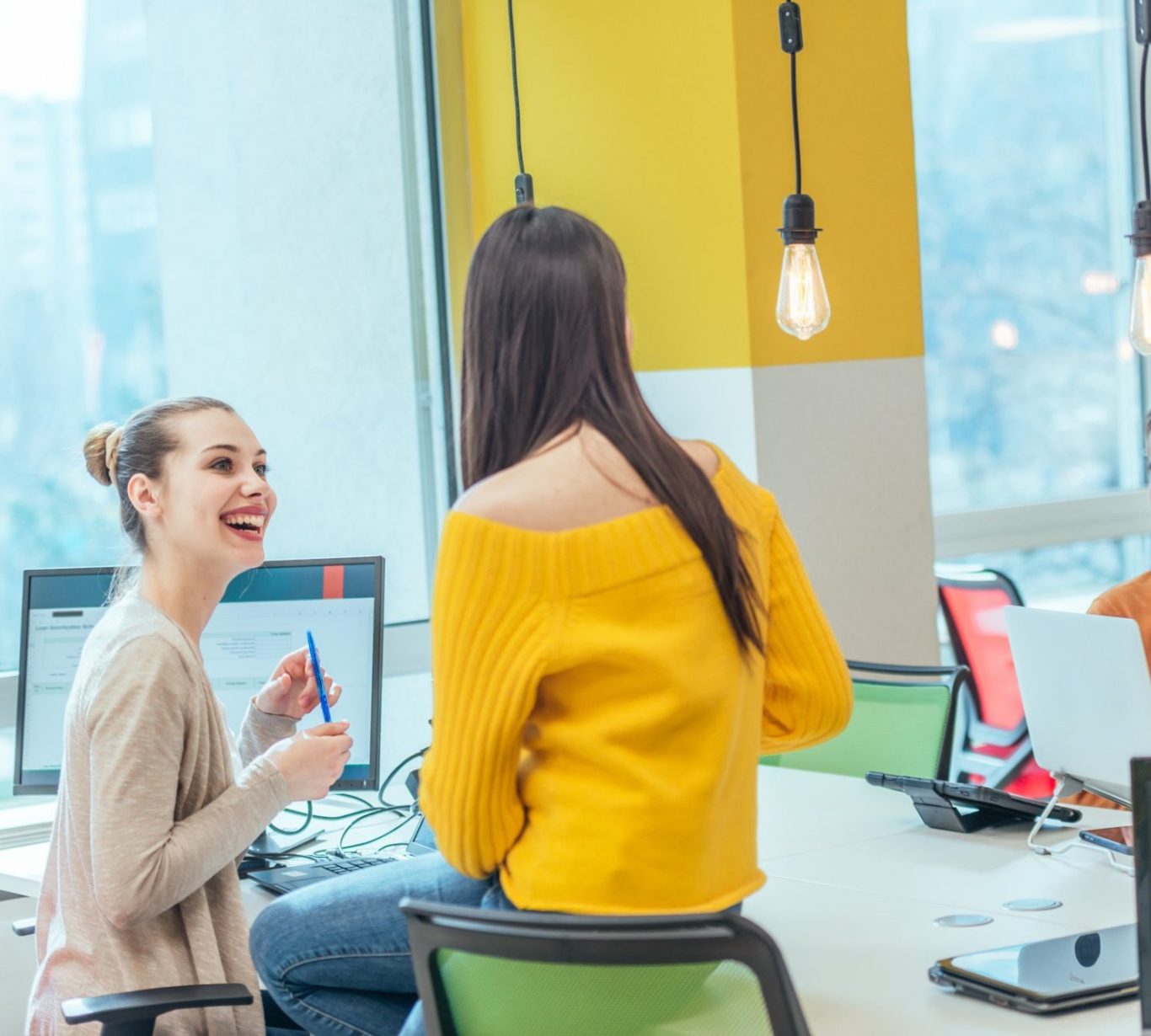 Gruppe von jungen Menschen in einem modernen Büroumfeld, die an einem Tisch arbeiten und kommunizieren.